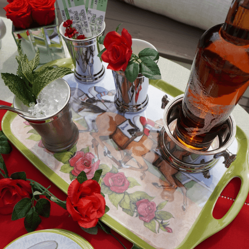 Horse-themed gift tray on table with two glasses of iced drinks and red roses