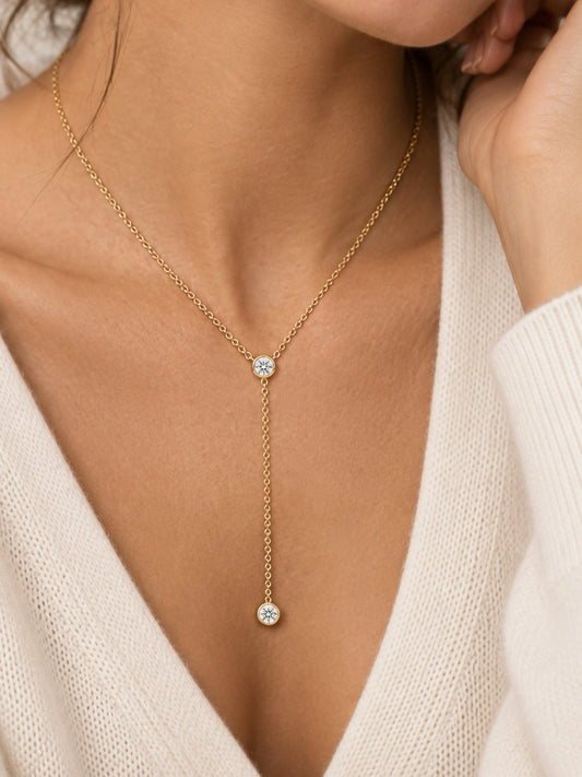 Gold-tone lariat necklace worn: round bezel stones on V drop with dangling charm