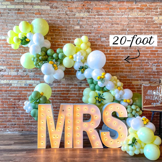 Balloon garland kit with lemon yellow, green, and white balloon clusters and letter balloons
