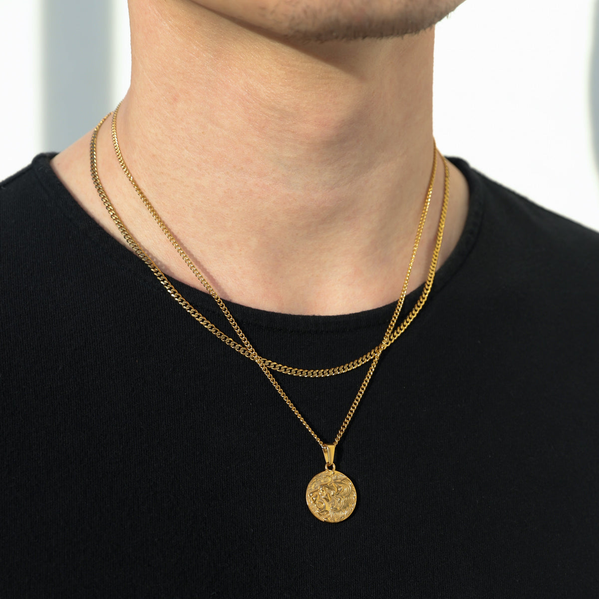 Gold coin pendant necklace with round lion medallion and fine chain on a man’s neck.