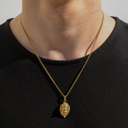 Gold-tone lion head pendant necklace with lion head charm and fine chain, worn at neckline.