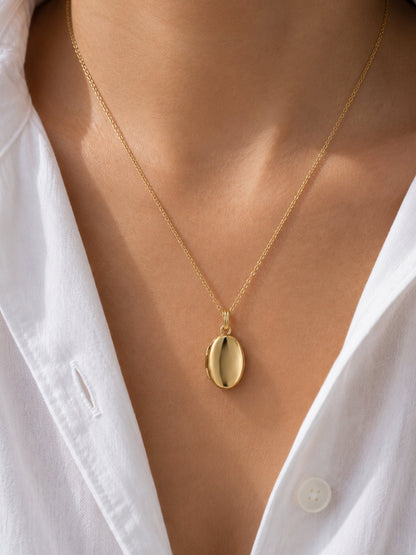 Gold oval locket pendant necklace with polished oval front close-up