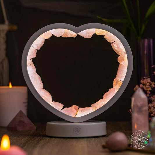 Heart-shaped rose quartz lamp with gray frame and illuminated white base.