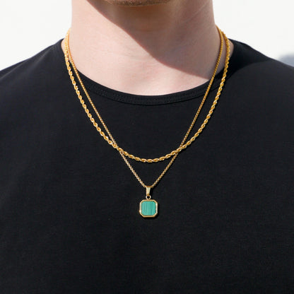 Gold chain necklace with green square pendant on black crewneck shirt