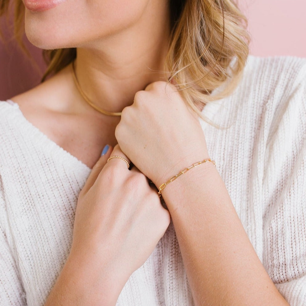 Gold-filled paperclip bracelet worn on the wrist, with slim rectangular links.