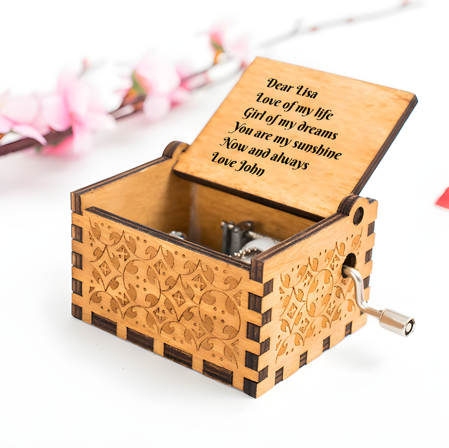 Engraved wooden music box with open lid, engraved message, carved sides, and crank