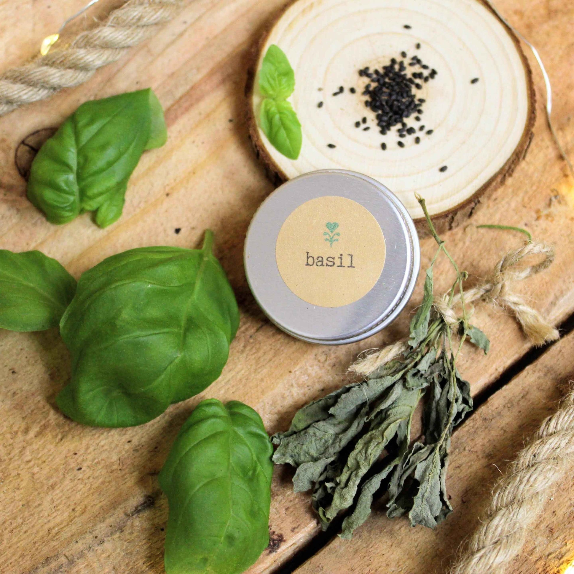 Basil seed tin with basil leaves, seeds, twine, and wood slice