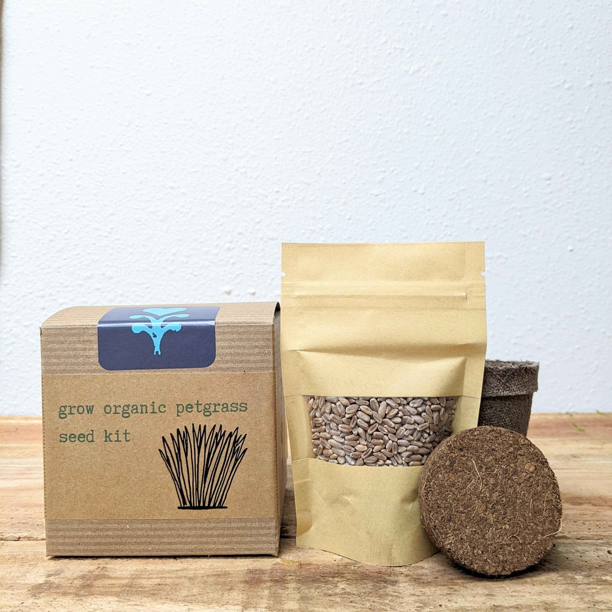 Petgrass grow kit contents: cardboard box, seed packet, and dark soil puck