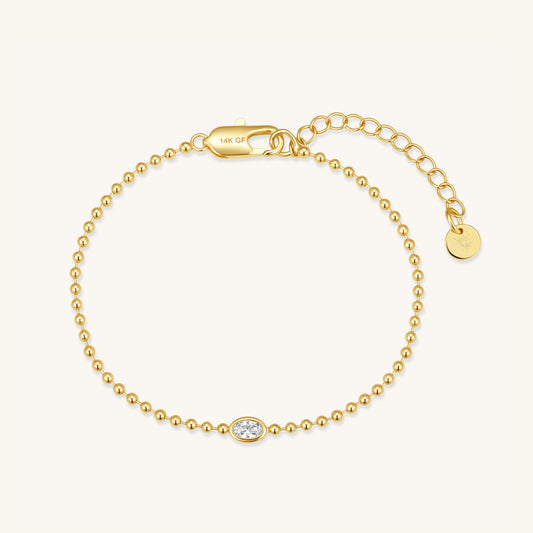 Gold beaded bracelet with oval center stone and small round charm