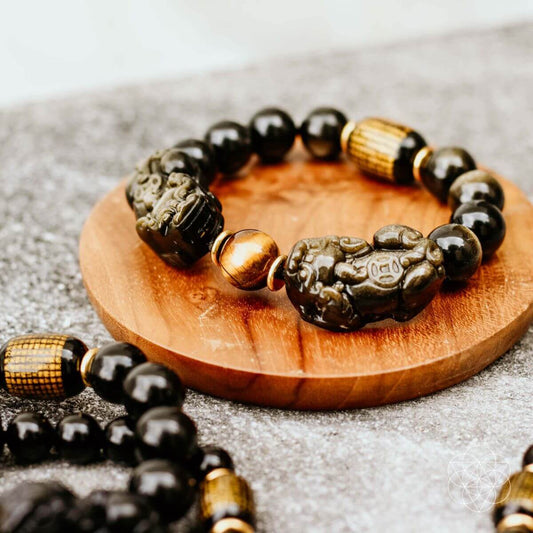 Black bead Pi Yao wealth bracelet with gold accents and carved lucky figure charms