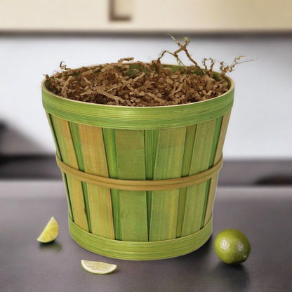 Green bamboo-style gift basket filled with shredded filler, with small citrus slices nearby
