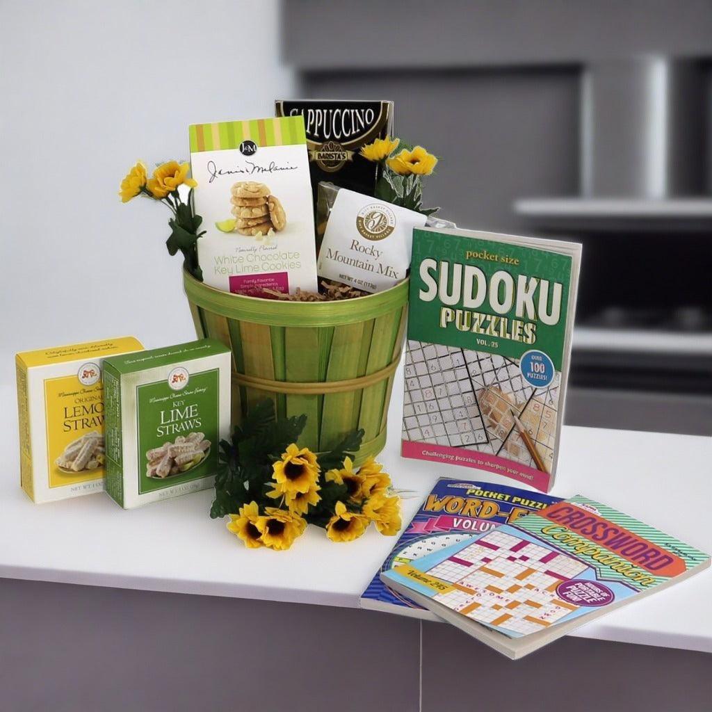 Gift basket with green bamboo-style container holding snack boxes, puzzle booklets, and flowers