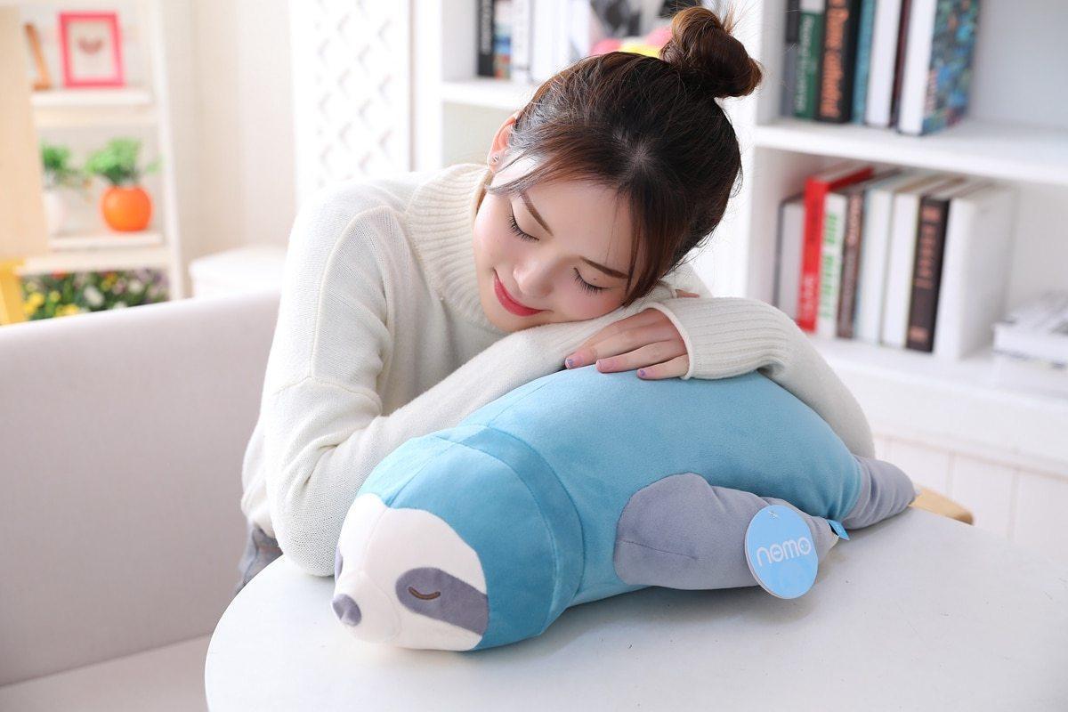 Blue and grey sleeping sloth plush with closed eyes, held while resting