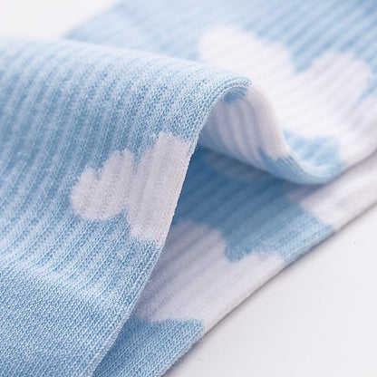 Light blue sock with white cloud motif, close-up of ribbed fabric.