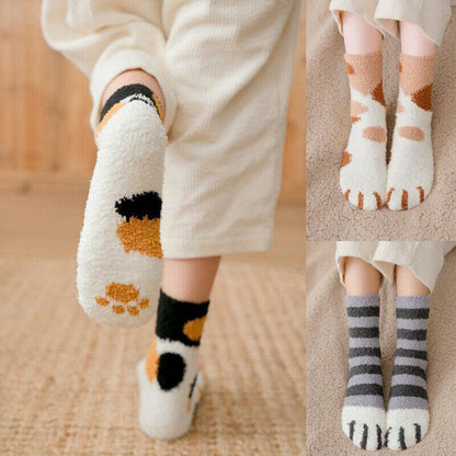 White fuzzy socks with black and tan cat paw designs and matching toe pattern