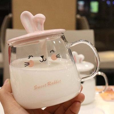 Glass bunny mug with bunny-ear lid and face print, held close-up
