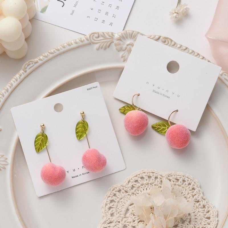Drop earrings with pink pom-pom balls and green leaf charms on gold ear wires
