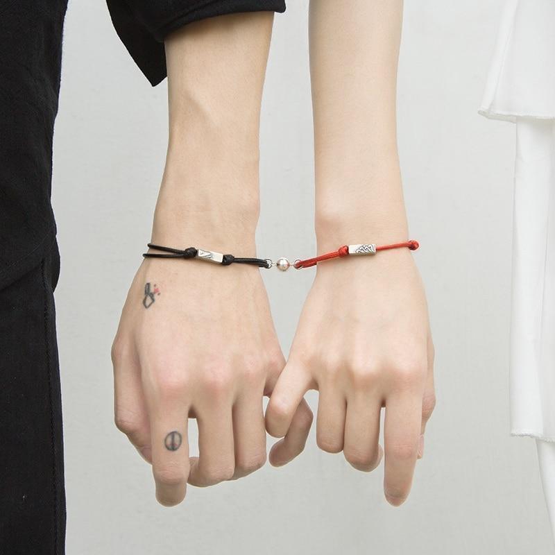 Magnetic attraction bracelet set on hands, black and red braided cords with silver tube ends