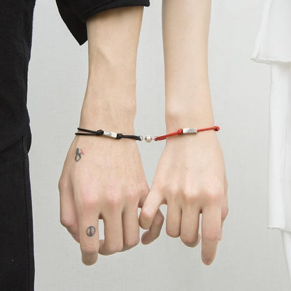 Magnetic attraction bracelet set on hands, black and red braided cords with silver tube ends
