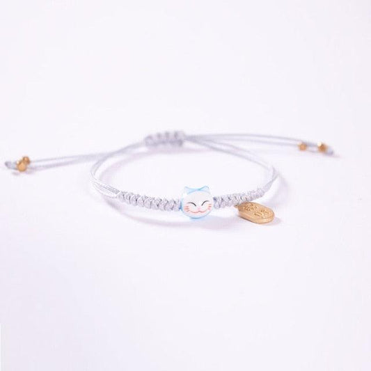 White cord cat charm bracelet with light blue cat bead and gold-tone heart tag