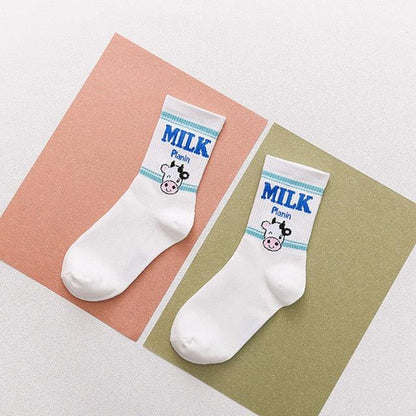 Pairs of white socks with blue “MILK” text and cow face graphic