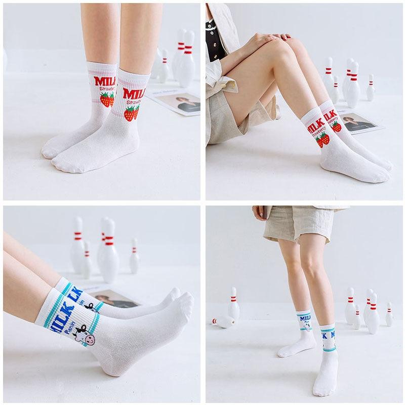White crew socks with “MILK” strawberry and cow graphics worn on model legs