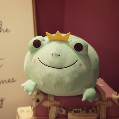 Green frog plush with yellow crown, embroidered smile, and brown eye patches