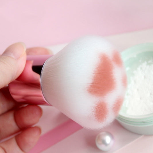 Cat paw makeup brush with white bristles and a pink handle, close-up