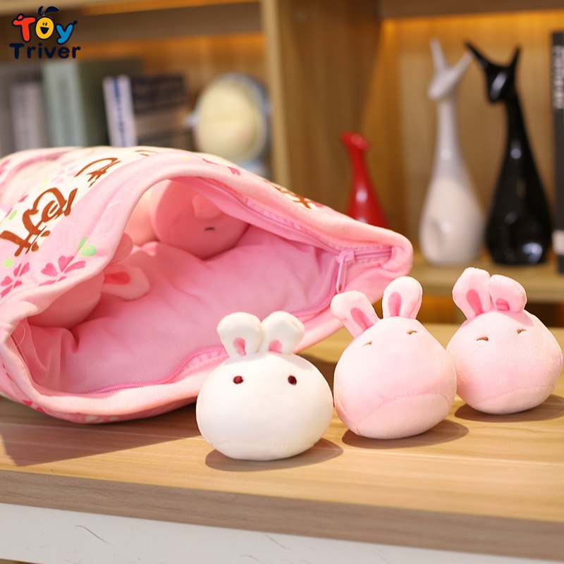 Pink bunny pillow plush pouch with three bunny plush toys on a wooden surface