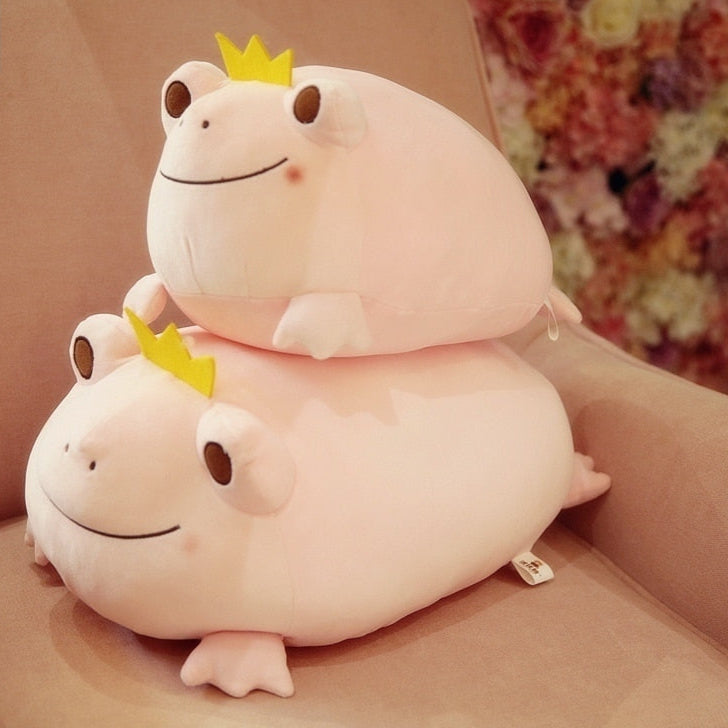 Stack of white frog plushies with yellow crowns, smiling embroidered faces