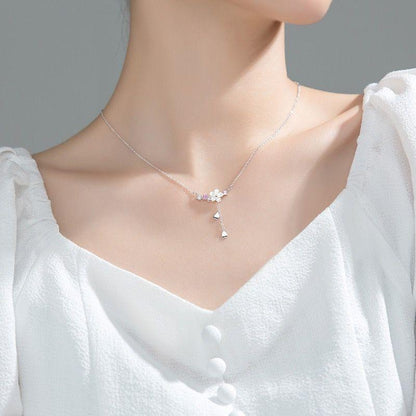 Silver-tone sakura pendant necklace worn on neckline, with flower charm and pink stones