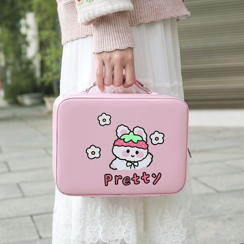 Pink kawaii animal makeup storage case with lid and handle, held by a person outdoors.