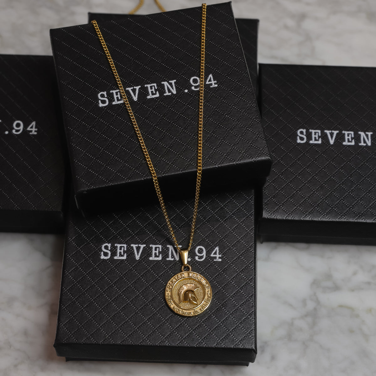 Gold Spartan warrior pendant necklace on black gift box, round coin pendant visible.
