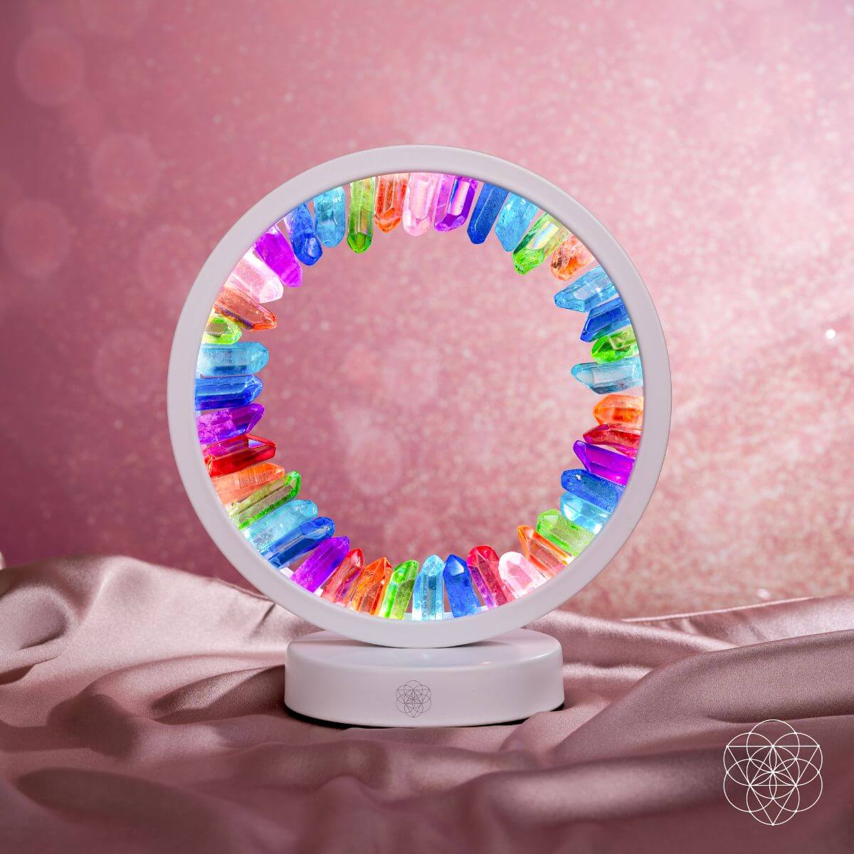 Rainbow crystal aura lamp with glowing multicolor ring on draped fabric