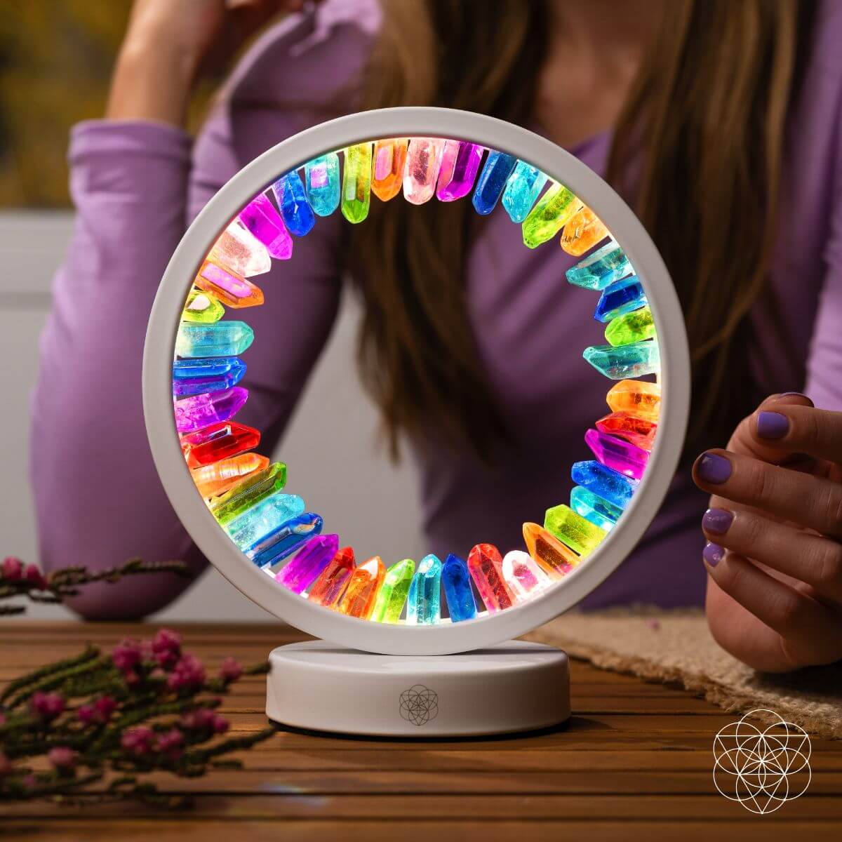 Circular multicolor aura lamp, shown with hands near the glowing ring and base
