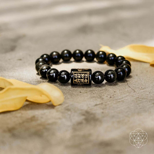Black beaded protection bracelet with gold-tone square charm centerpiece