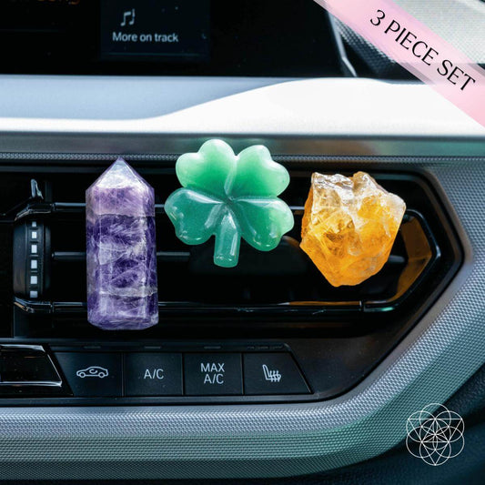Three crystal car fresheners: purple prism, green clover, orange crystal on air vent