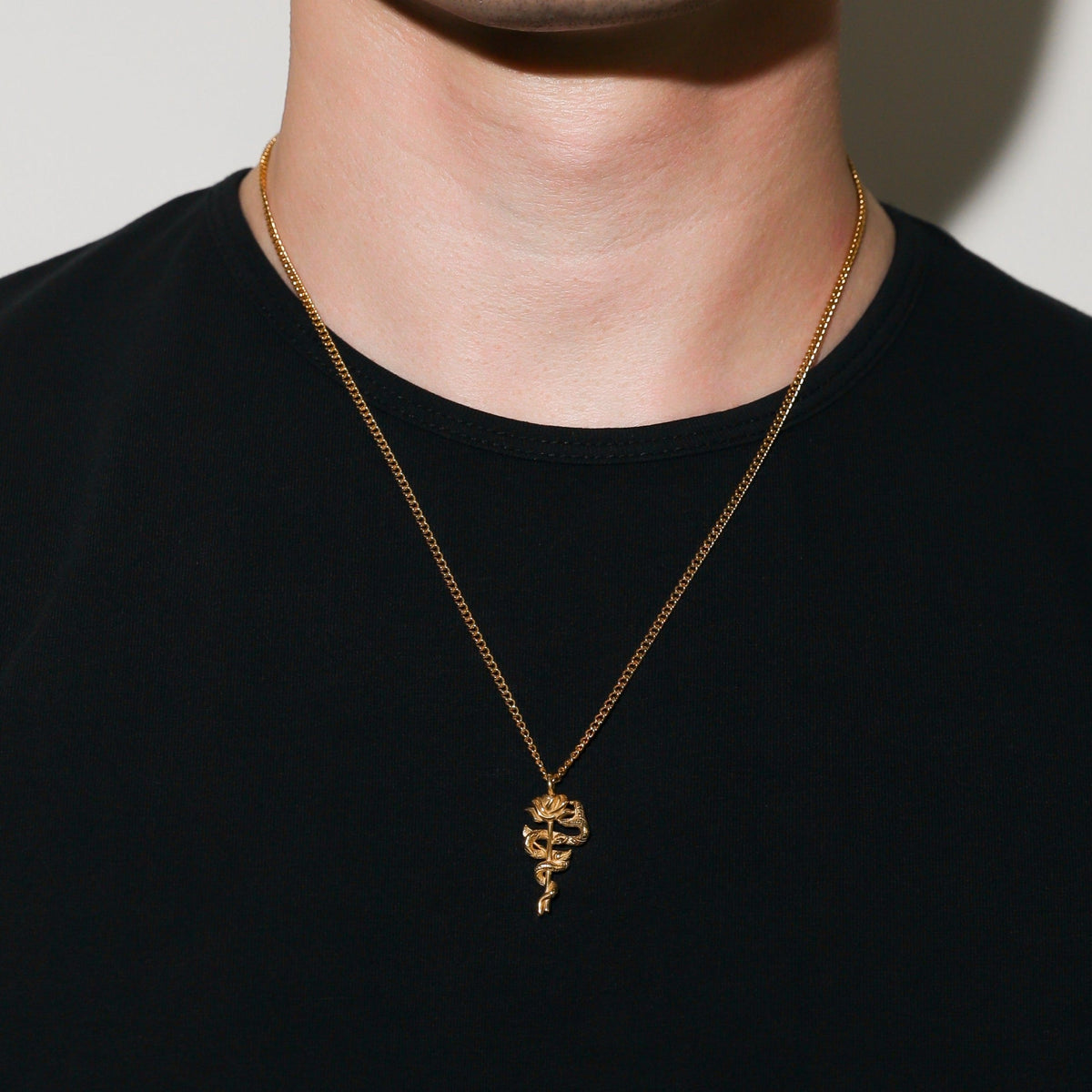 Gold serpent rose pendant necklace with coiled rose charm centered on the chest
