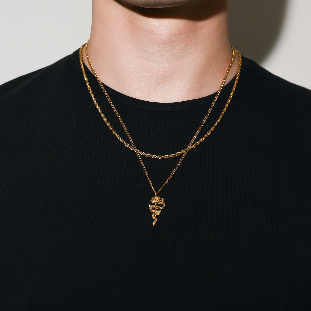 Gold serpent rose pendant necklace with coiled rose pendant hanging on a double chain