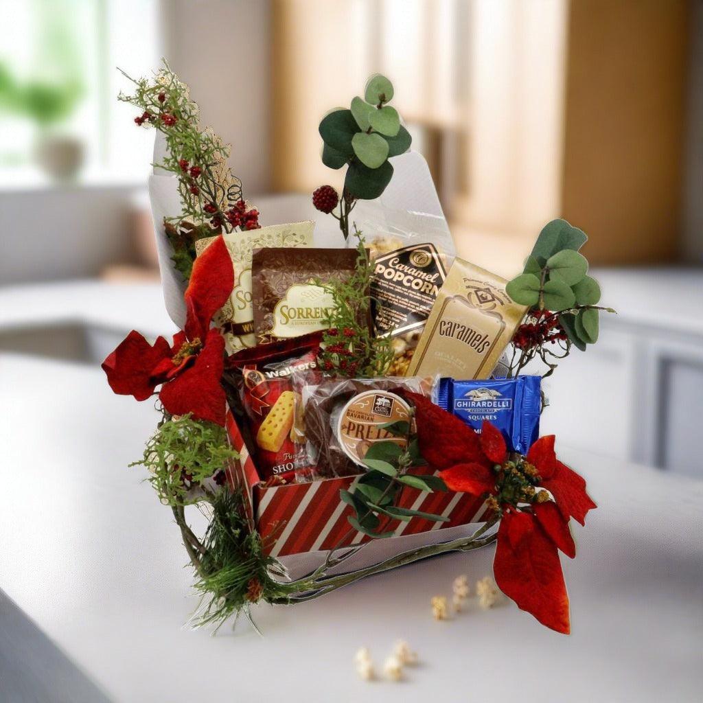 Wrapped gift box with assorted chocolates and candy, decorated with green eucalyptus stems