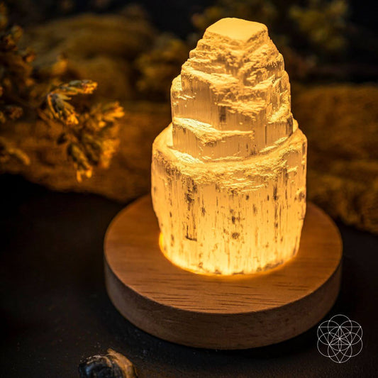 Selenite cleansing lamp glowing amber inside selenite on round wooden base