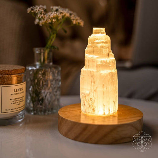 Selenite cleansing lamp with glowing crystal on round wooden base