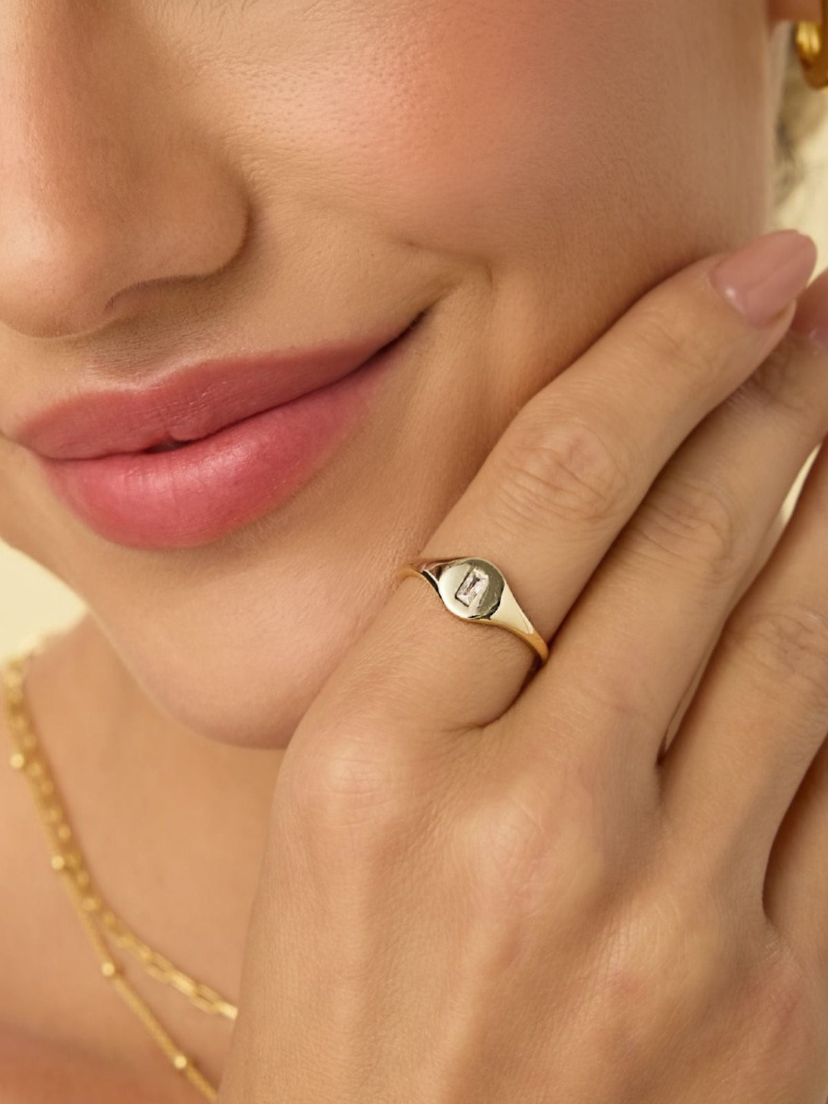 Gold-tone signet ring with small square baguette crystal at the center
