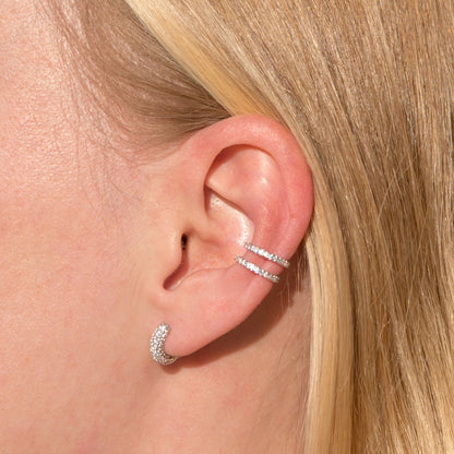 Pave huggie hoop earrings in silver on an ear