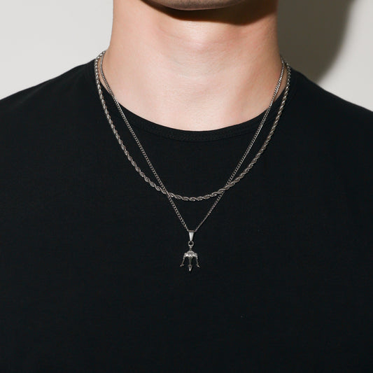 Silver trident pendant necklace set with two layered chains on a model’s neck