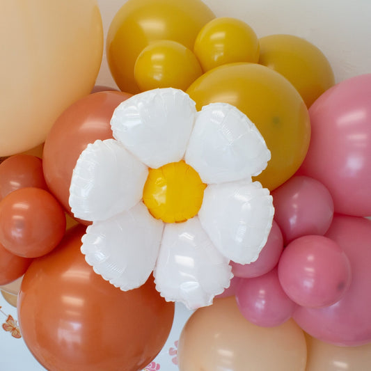 Pastel balloon cluster with a white daisy foil balloon featuring a yellow center