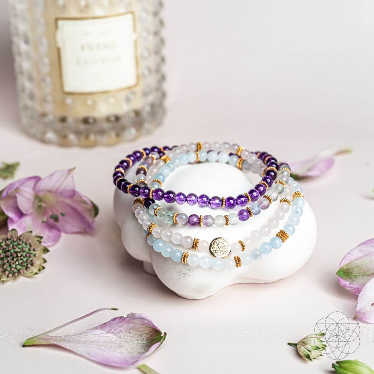 Four-strand gemstone bracelet set with purple and light blue beads on a white display stone