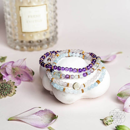 Four-strand gemstone bracelet set with purple and light blue beads on a white display stone