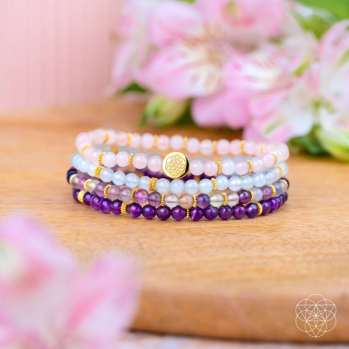 Stacked gemstone bracelets with amethyst purple and aquamarine blue beads on wooden surface