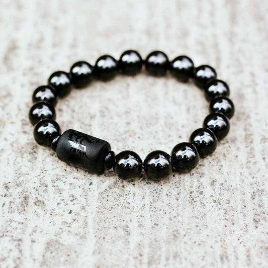 Black beaded bracelet with glossy round stones and a dark etched center bead